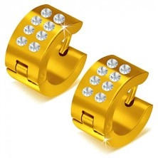 Glänzende rundliche Ohrringe goldener Farbe, klare Steinchen
